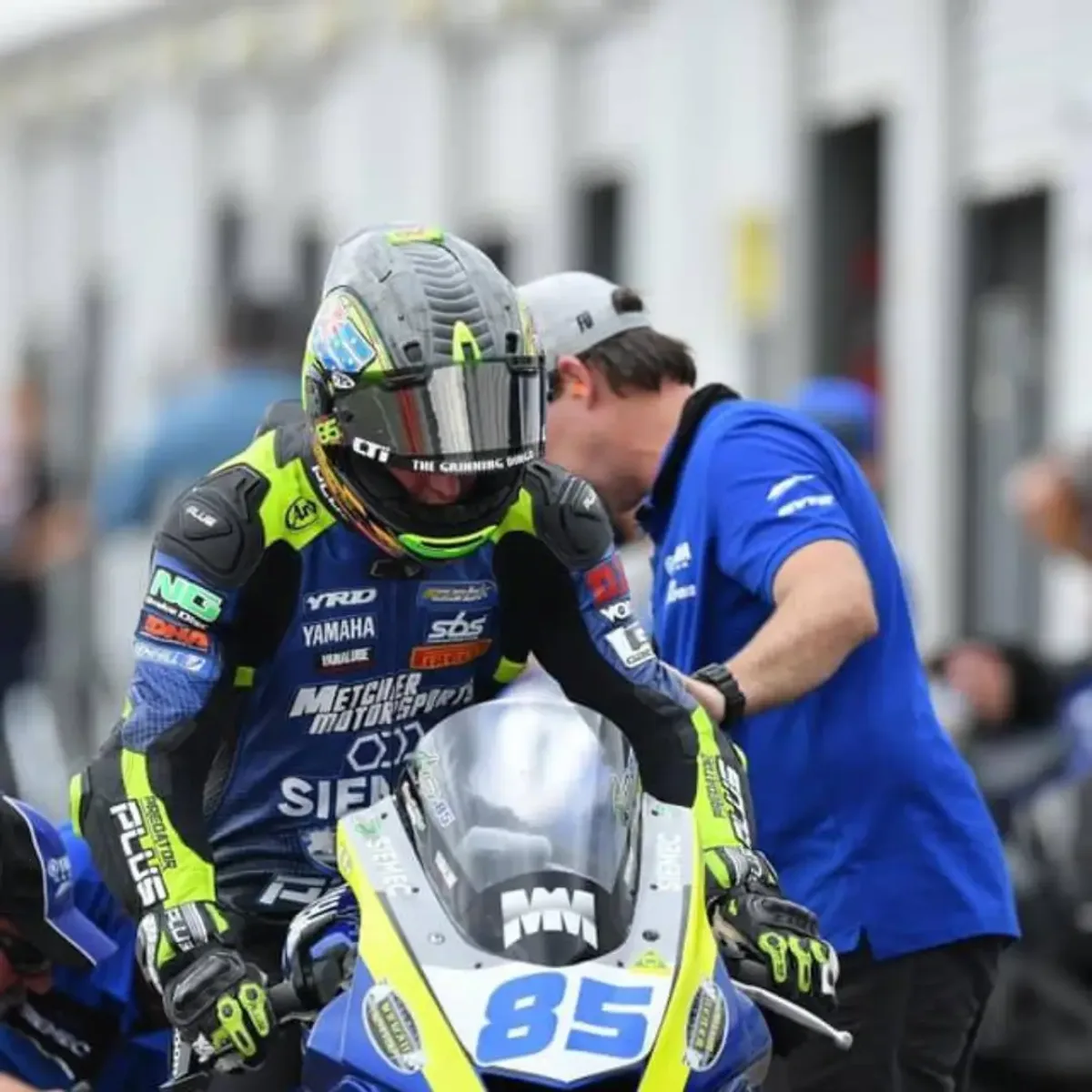 Crew member and rider working together in the pit box